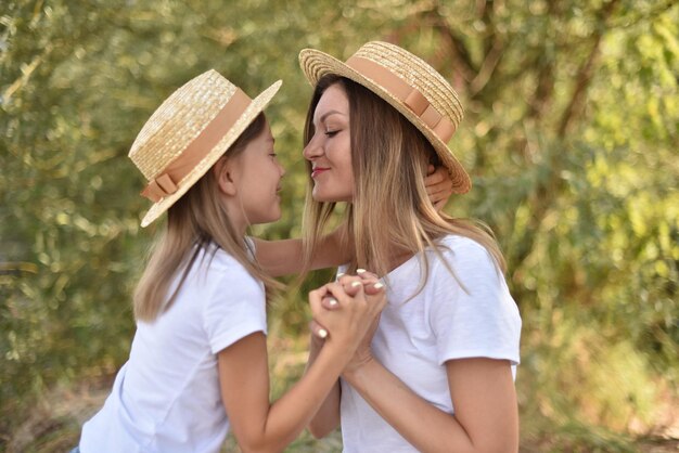 Mother and daughter lovingly look at each other on green tree background in park family on vacation