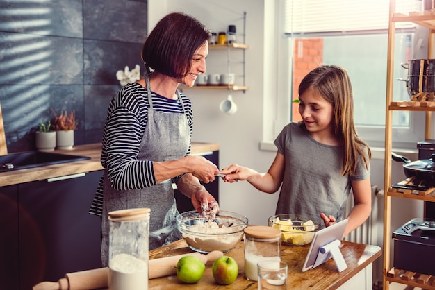 Mother and daughter making dough for apple pie