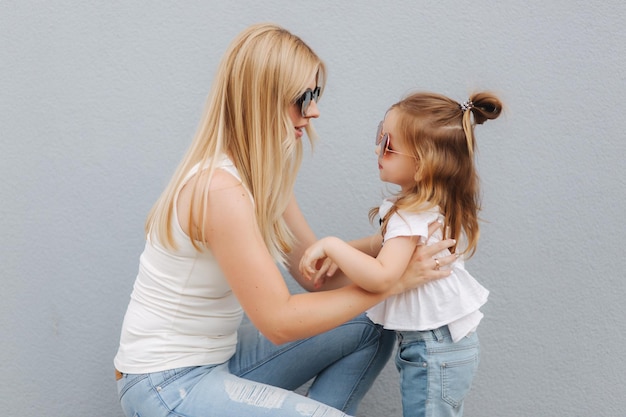 Mother and daughter outdoors in city playing and having fun Fashion happy mother and child daughter having fun together in the city