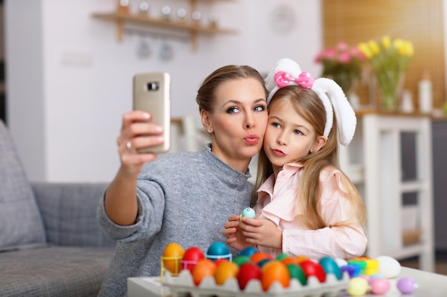 mother and daughter painting Easter eggs and taking selfie