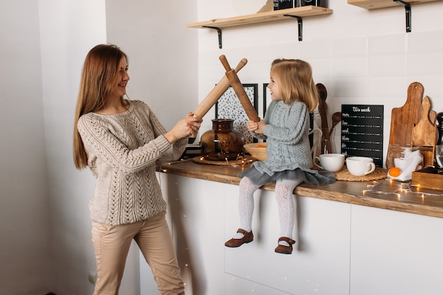 Mother and daughter playing in kitchen at home. 