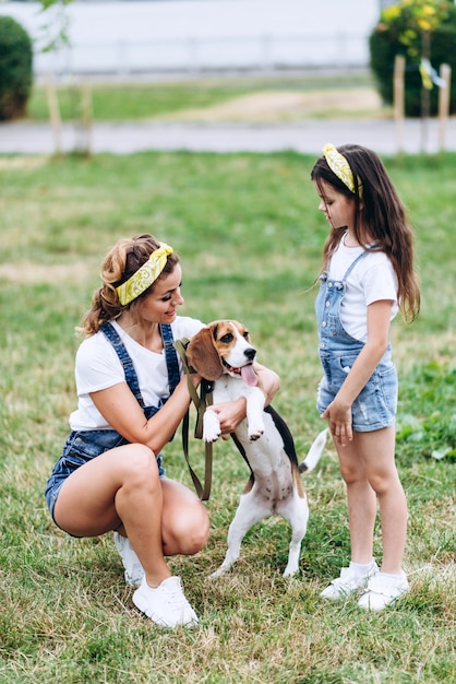 Mother and daughter playing with dog outdoor.