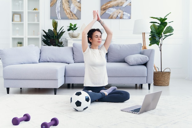 Mother and daughter practicing online yoga lesson at home