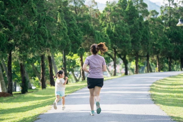 Mother and daughter runners are jogging in the park Evening Family activities Mother and son in sportswear are running and having fun