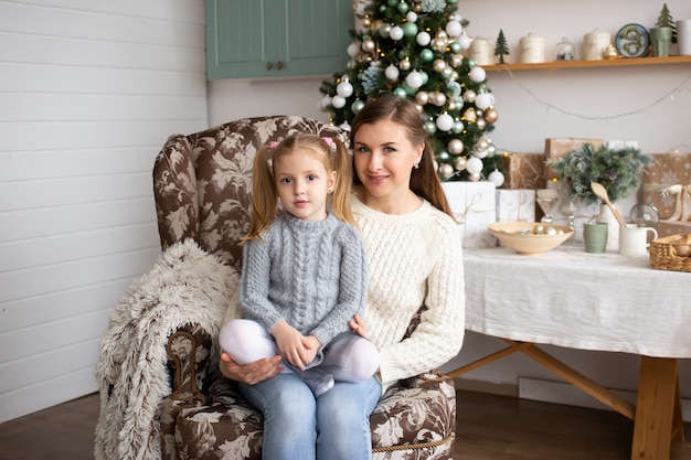 Mother and daughter sitting in Christmas background