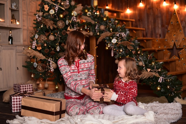 The mother and daughter sitting on the floor near Christmas tree