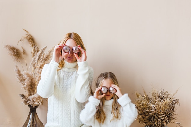 Mother and daughter sitting and holding Christmas ornaments