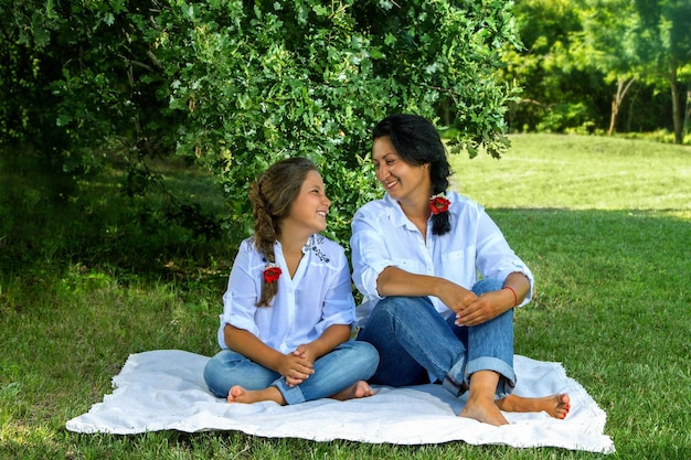 Mother and daughter sitting under an oak tree in a park