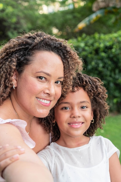 Mother and daughter smiling and hugging in a park