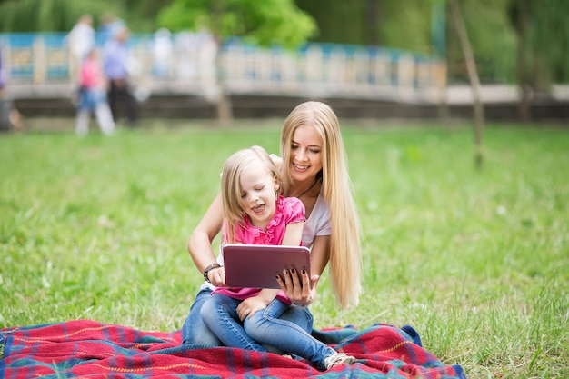 Mother and daughter take a selfie using a tablet in nature