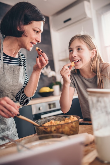 Mother and daughter tasting apple pie filling