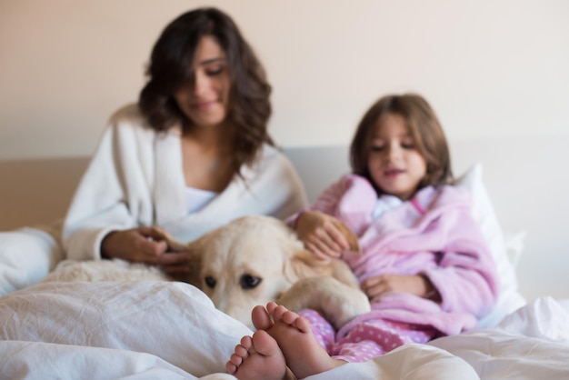 Mother and daughter with dog in bed - focus on feet