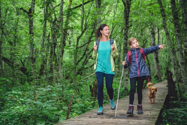 Mother and daughter with a dog hiking in the forest