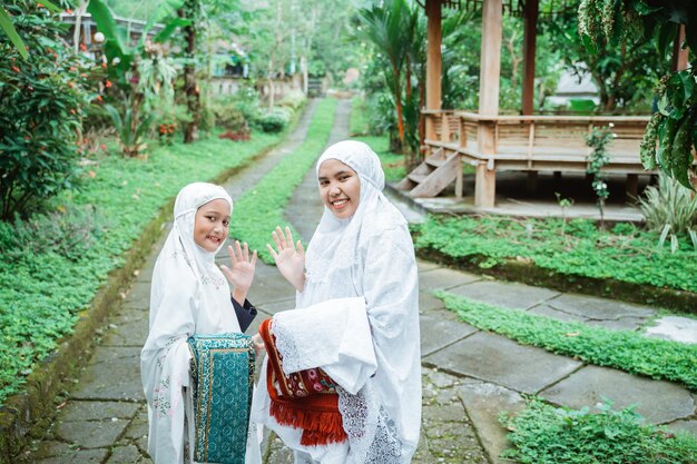 Mother and daughter with hijab walking to the mosque to do idul fitri prayer