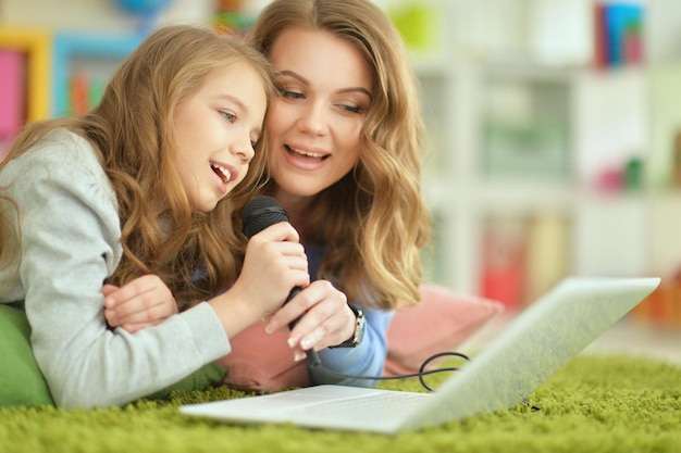 Mother and daughter with laptop on green carpet