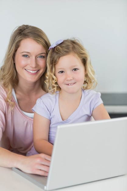 Mother and daughter with laptop at kitchen table