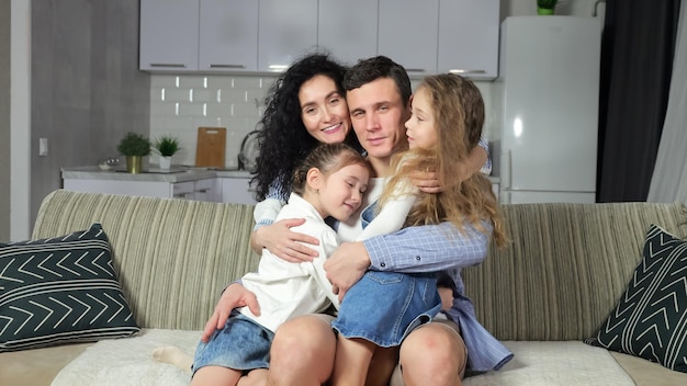 Mother and daughters run to hug father watching tv on sofa