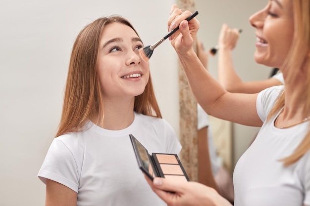 Mother doing makeup for daughter at home