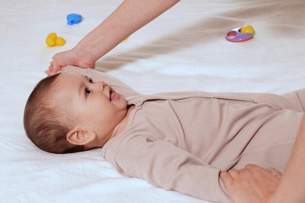 Mother doing massage on her healthy infant baby Caring Woman Making Gymnastics To little Baby