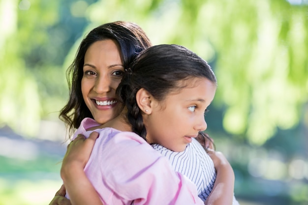 Mother embracing her daughter in park