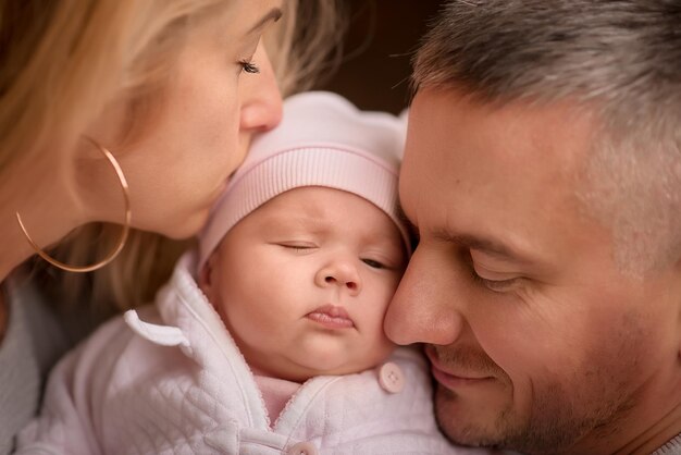 Mother  father  family with a newborn baby on a walk in the park in the forest parents kiss the child