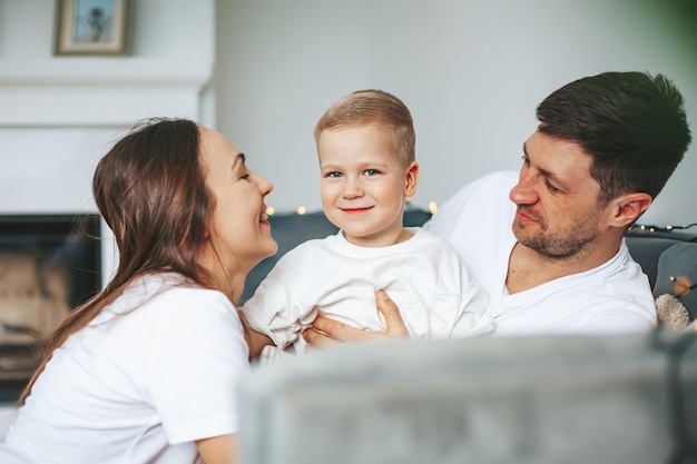 Mother and father hugging their little son on a couch