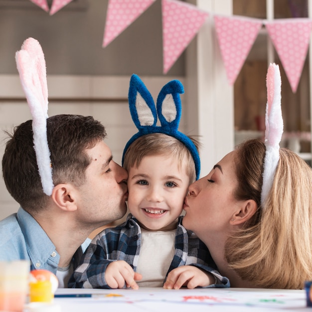 Mother and father kissing adorable little boy