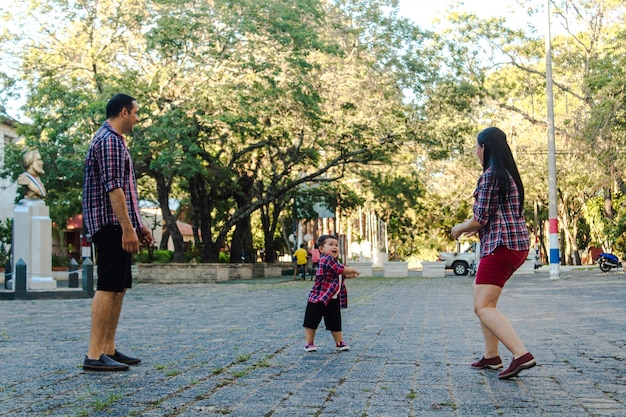 Mother and father playing with their happy child in the square