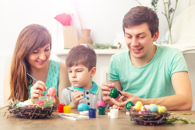 Mother father and son are painting eggs Happy family are preparing for Easter