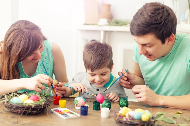 Mother father and son are painting eggs Happy family are preparing for Easter