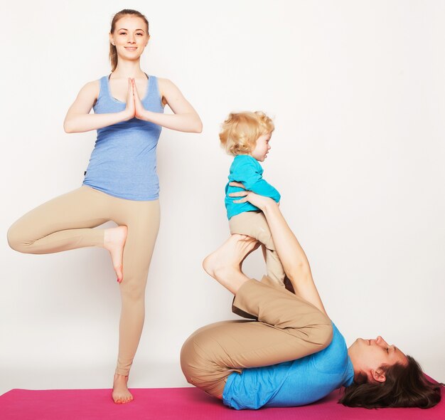 Mother, father and son doing yoga over white background