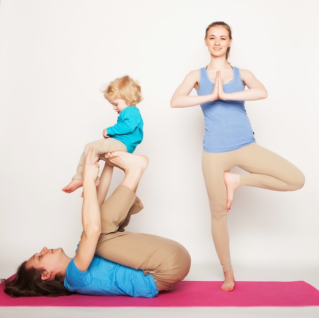 Mother, father and son doing yoga over white background