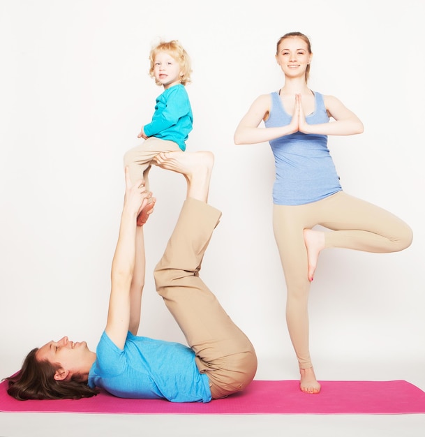 Mother, father and son doing yoga over white background