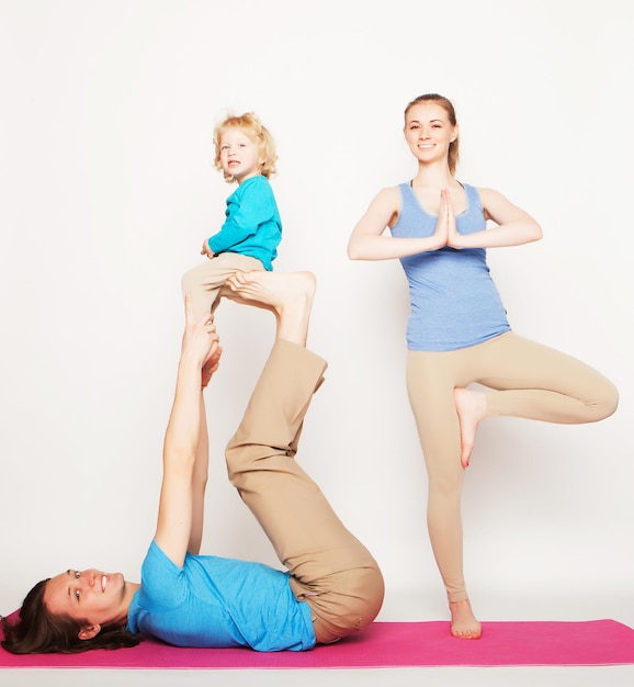 Mother, father and son doing yoga over white background