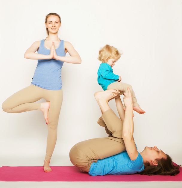 Mother, father and son doing yoga over white space