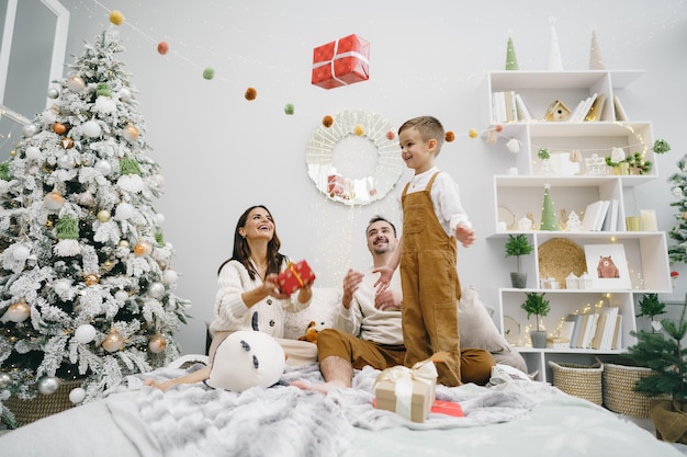 Mother father and son having fun on bed on christmas day