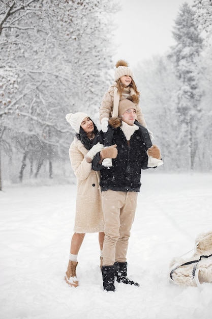 Mother father and their little daughter playing outdoors at winter day