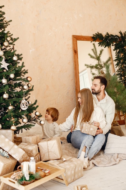 Mother father and their son sitting near Christmas tree at home