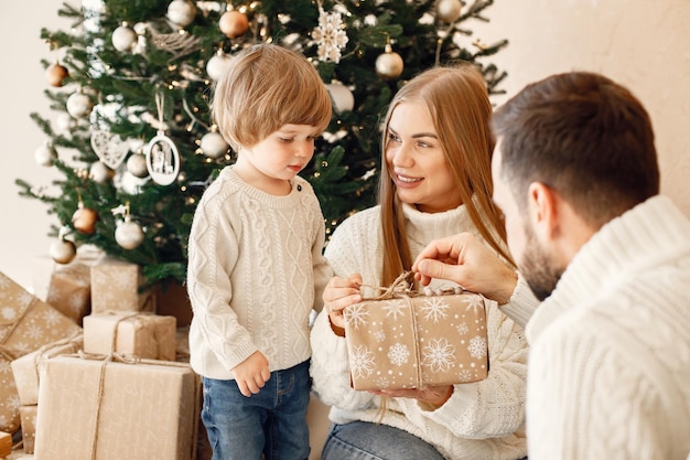 Mother father and their son sitting near Christmas tree at home