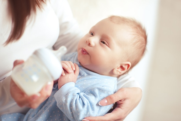 Mother feeding baby boy with milk in bottle