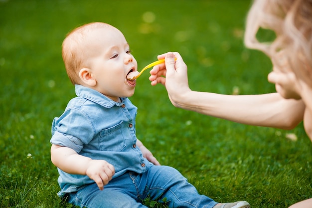 Mother feeds the baby with a spoon in the Park