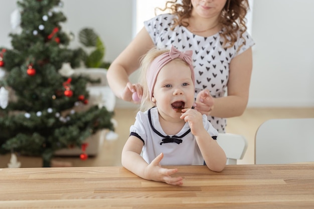 Mother fixing her daughter's cochlear implant hearing aid on christmas tree background deafness and diversity concept Innovative technologies i