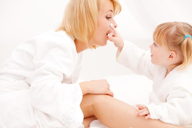 Mother and girl applying cream