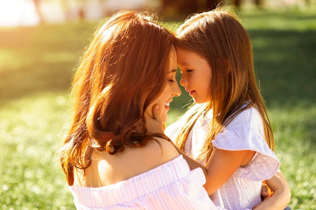 Mother and girl looking at each other holding head to head outdoors