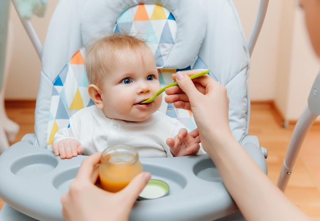 Mother gives fruit sauce to babymom feeds baby on highchairbaby food