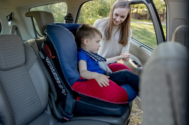 Mother gives the phone little boy sitting in a car seat Safety of transportation of children