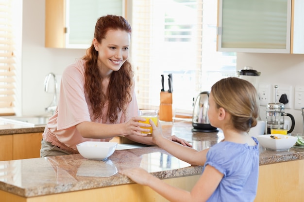 Mother giving her daughter orange juice