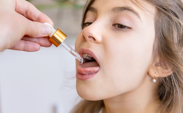 Mother giving vitamin drops with dropper to her child. dietary supplements for kids. Selective focus.