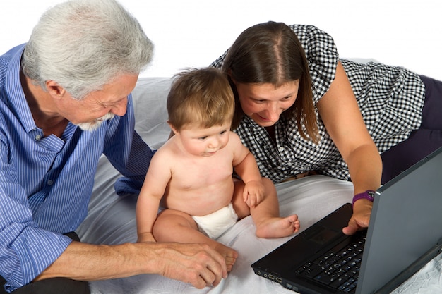 Mother and grandfather with baby play with pc