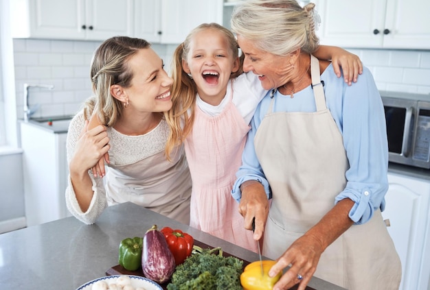 Mother grandma and child cooking as as happy family in a house kitchen with organic vegetables for dinner Grandmother mom and young girl laughing bonding and helping with healthy vegan food diet